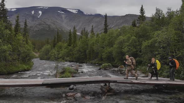 Aerial View Group of Hikers with Large Backpacks Cross the Bridge