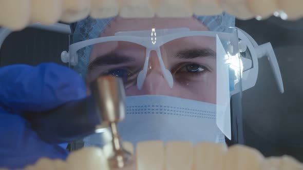 View From Open Mouth of Dentist in Protective Uniform Spraying Patient Teeth with Water