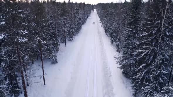 Aerial view of a car driving in the snowy forest in Estonia.