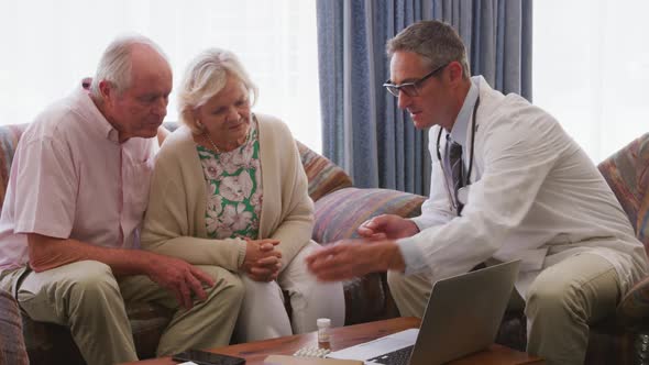 Senior couple talking with a doctor in retirement house