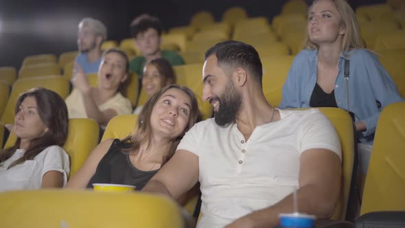 Portrait of Cheerful Young Caucasian Woman Dating with Handsome Middle Eastern Man in Cinema. Happy