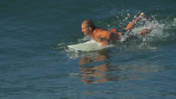 A male surfer rides a wave on a longboard surfboard.