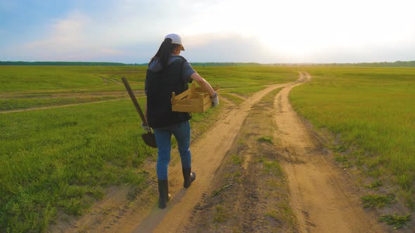 Woman Farmer Holding Shovel in His Hand Walking Across Green Field a Pile of Dirt Soil