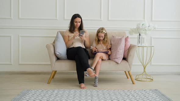 Young Woman with Daughter Using Gadgets on Sofa / Videohive, Stock footage, Technology