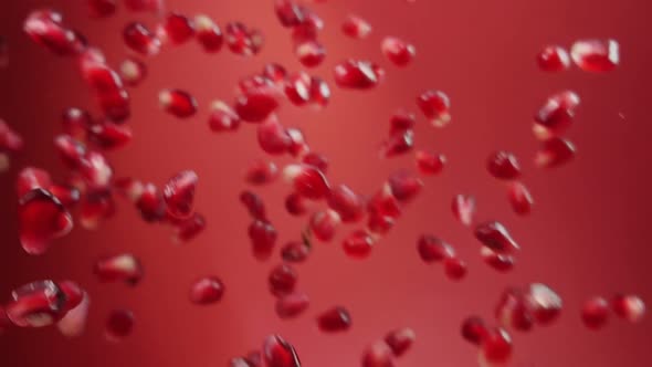 Juicy Red Grains of Ripe Pomegranate Are Bouncing on the Ruby Red Background