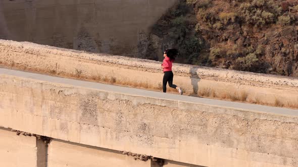 Asian woman jogging across the Salmon Falls Dam in Idaho