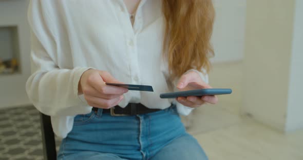 Woman Making a Payment Using Credit Card and Smartphone in Modern Contemporary House / Electronic