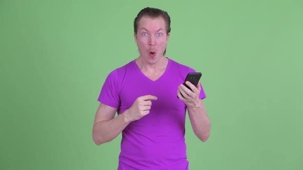 Happy Young Handsome Man Using Phone and Looking Surprised