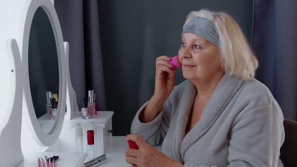 Old Senior Woman Grandmother Taking Care of Skin, Applying Anti-wrinkle Foundation with Sponge