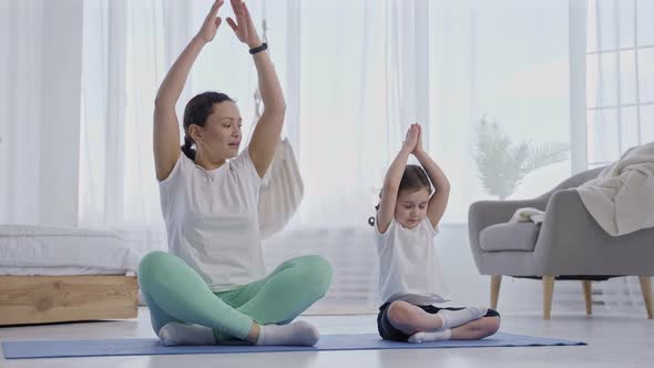 Mother Teaching Girl to Do Yoga Exercises Together