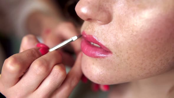 Hands of Professional Makeup Artist Applying Lipstick on Model's Lips Working in Beauty Fashion