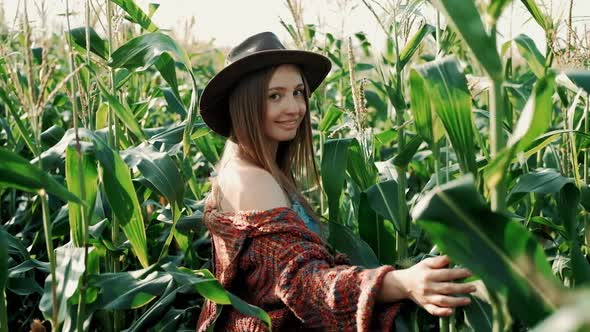 Young Farmer Girl in a in a Vintage Dress and Hat, on a Corn Field, Goes Through the Tall Corn