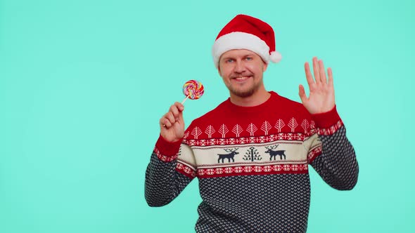 Joyful Man in Red New Year Sweater Hat Holding Candy Striped Lollipops Dancing Making Silly Faces