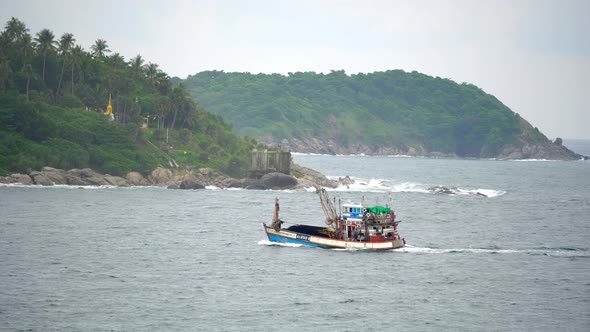 A Small Cargo Ship Sails Near a Beautiful Tropical Island in The Sea