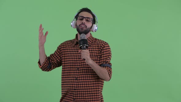 Happy Young Bearded Persian Hipster Man Singing with Microphone