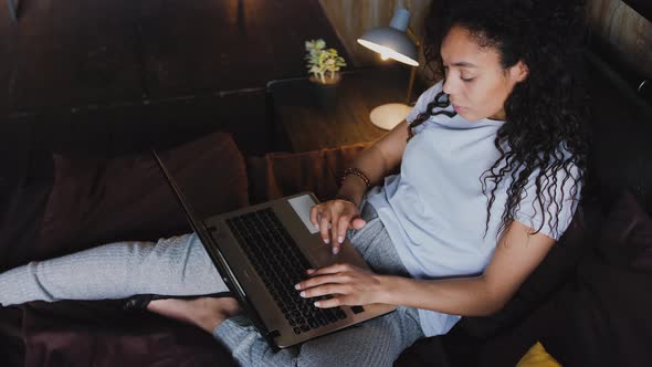 Young Attractive AfricanAmerican Woman Using Laptop Computer in the Bed Portrait High Angle View