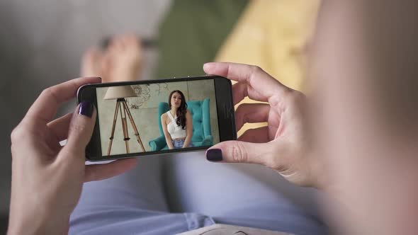 Woman Watching Webinar Blogger Video on Her Smart Phone While Lying on Sofa