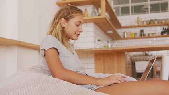 Woman using laptop while sitting on a bean bag indoors