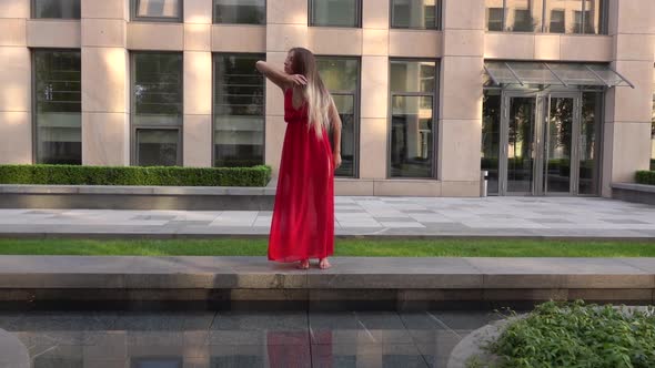 Beautiful Young Girl Dancing on the Street of a Modern City and Is Reflected in the Water. She Is