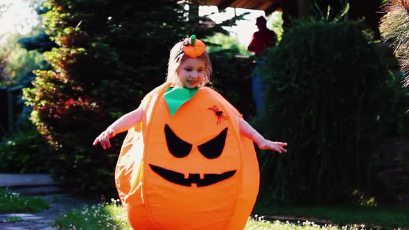 Young Beautiful Cute Girl of European Appearance in a Pumpkin Costume Jumps and Smiles Cutely