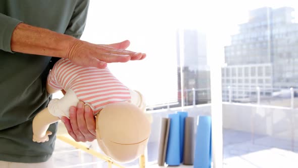 Male paramedic rubbing dummy back while training