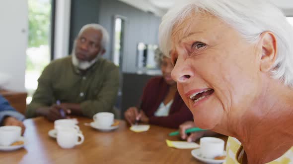 Happy senior diverse people drinking tea and playing bingo at retirement home