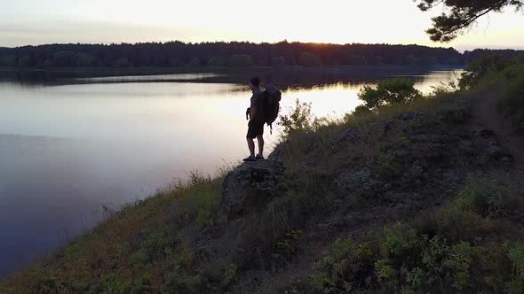 Silhouette Of Hiker Man. Adult man with backpack looking beautiful landscape nature near river