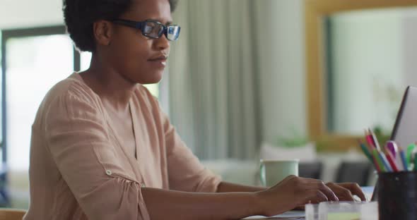 Happy african american woman sitting at table using laptop