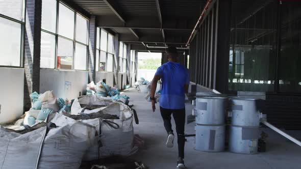 African american man wearing sports clothing jogging through an empty urban building