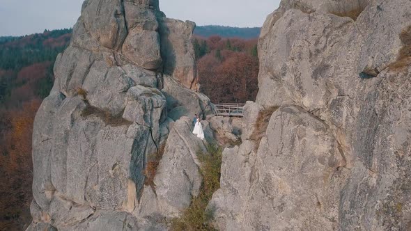 Newlyweds Stand on a High Slope of the Mountain, Groom and Bride, Arial View