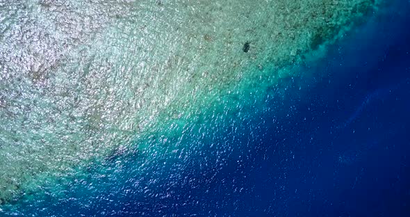 Wide angle aerial travel shot of a sandy white paradise beach and aqua blue ocean background 