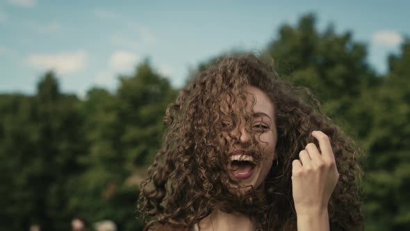 Camera tracking smiling young caucasian woman with curly hair dancing at music festival. Shot with R