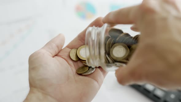 A Man Hands are Calculating Expenses for a Month on Background of Calculator and Graphs