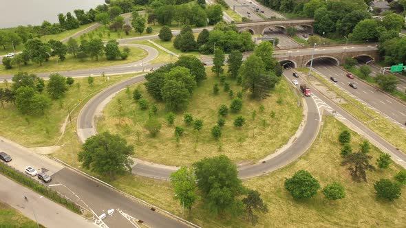 An aerial view over a parkway exit on a cloudy day. The drone orbits the circular exit in a counter-