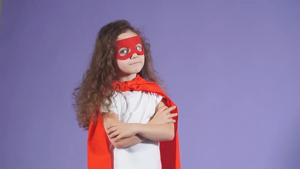 Portrait of Little Astronaut in Red Mask and Cloak Isolated Over Purple Background