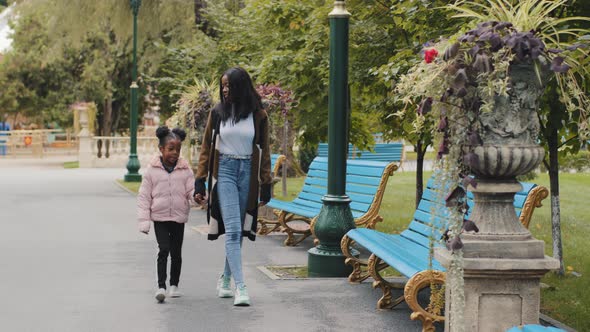 Mom and Daughter Walking in City Park on Weekend Mother Holding Little Girl Hand Happy African