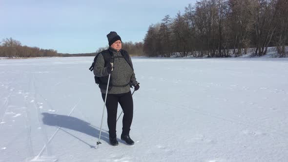 Active an Elderly Woman Engaged in Nordic Walking with Sticks in the Winter Forest