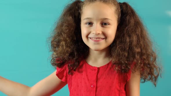 Portrait Funny on a Turquoise Background of a Happy Little Girl Smiling Child Looking at Camera Cute