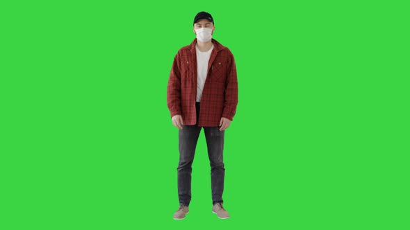 Young Man Gesturing And Wearing Mask Showing Thumb Up on a Green Screen, Chroma Key