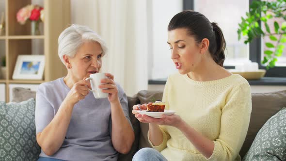 Old Mother and Adult Daughter Eating Cake at Home