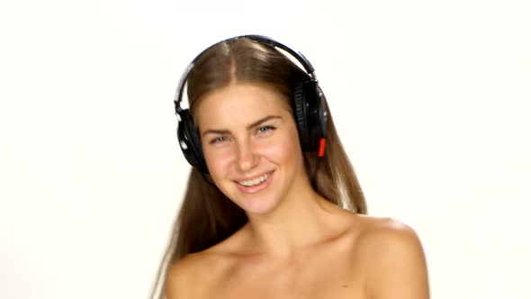 Beautiful Female in Headphones Listening To the Music with Fluttering on the Wind Hair Over White