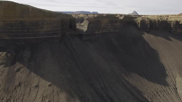 Flying over gap in sandy cliff wall viewing valley behind