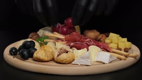 Preparation of cheese plate: parmesan, grapes, honey, nuts, grissini, jamon, prosciutto