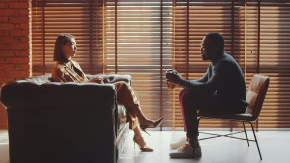 Black Man and Asian Woman Having Coffee and Discussing Business