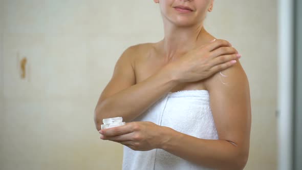 Middle Aged Woman Massaging and Applying Hydration Lotion to Body in Bathroom