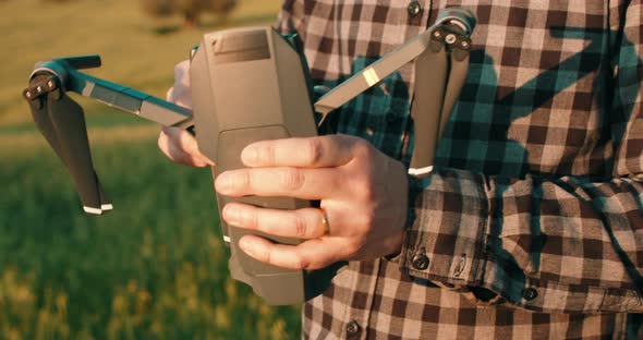 Close up shot of male person preparing drone for flight in nature during sunset.