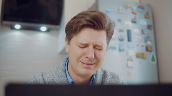 Young Attractive Man Crying While Sitting at Laptop