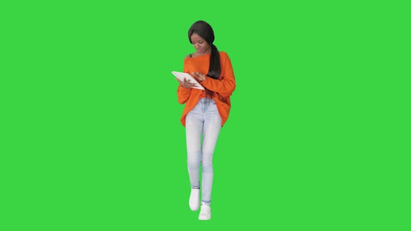 Smiling African American Woman Using Tablet Pc While Walking on a Green Screen, Chroma Key.