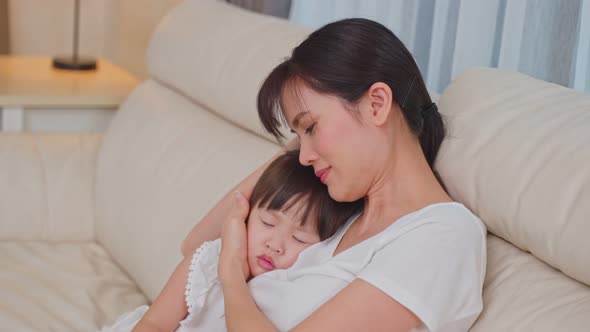 Asian beautiful loving mother hugging sleeping baby cute girl daughter in her arms with gently.