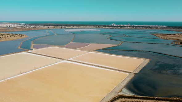 Aerial flyover colorful salt lakes in Portugal with Atlantic Ocean in background - Europe during sum